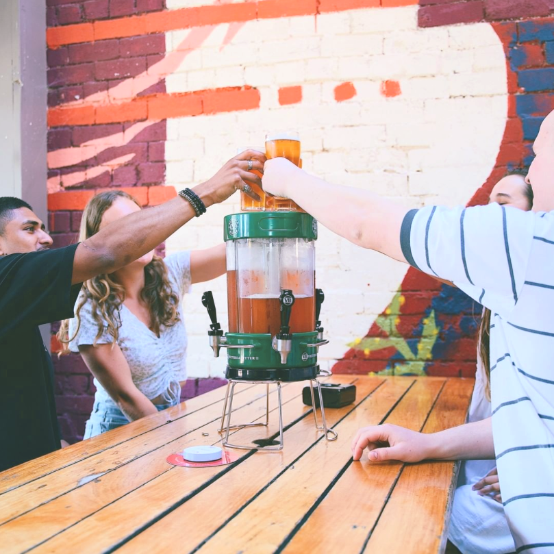 group of four people enjoying a beer with green tema keg on a table top