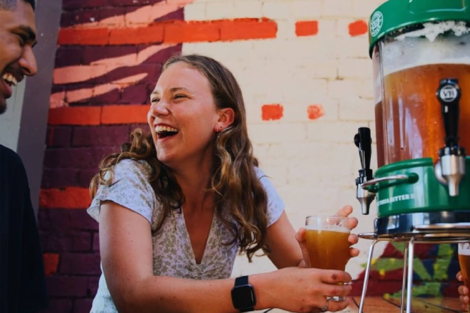 young professional woman enjoying glass of beer from green team keg
