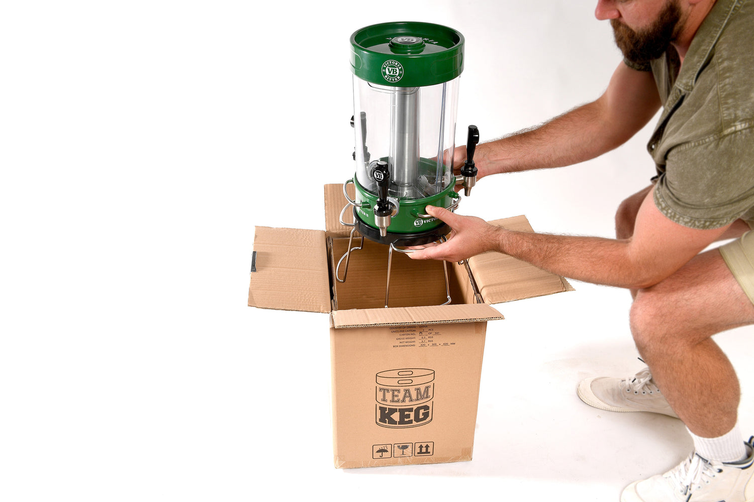 man with beard placing green vb team keg into a cardboard box